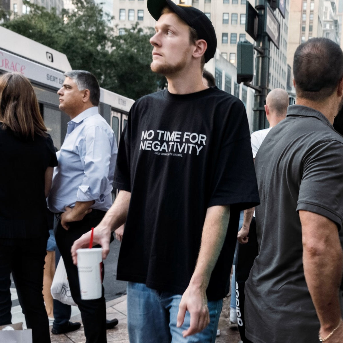 Man in a black NO TIME FOR NEGATIVITY t-shirt by Fully Conscious Apparel on a busy Manhattan sidewalk